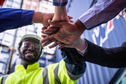 Supervisor leading a team building exercise with hands stacked in the center of a circle